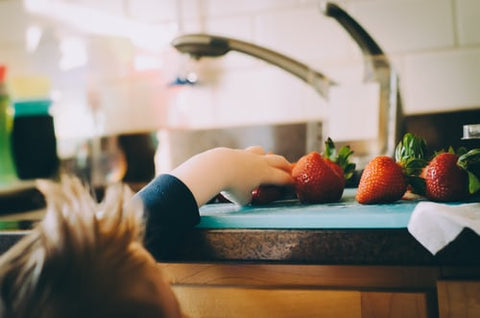 child reaching for a strawberry